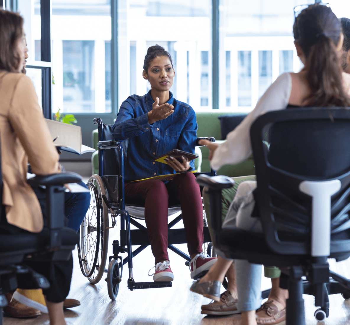 Image of a woman in a wheel chair, having a conversation with other co-workers in an office.