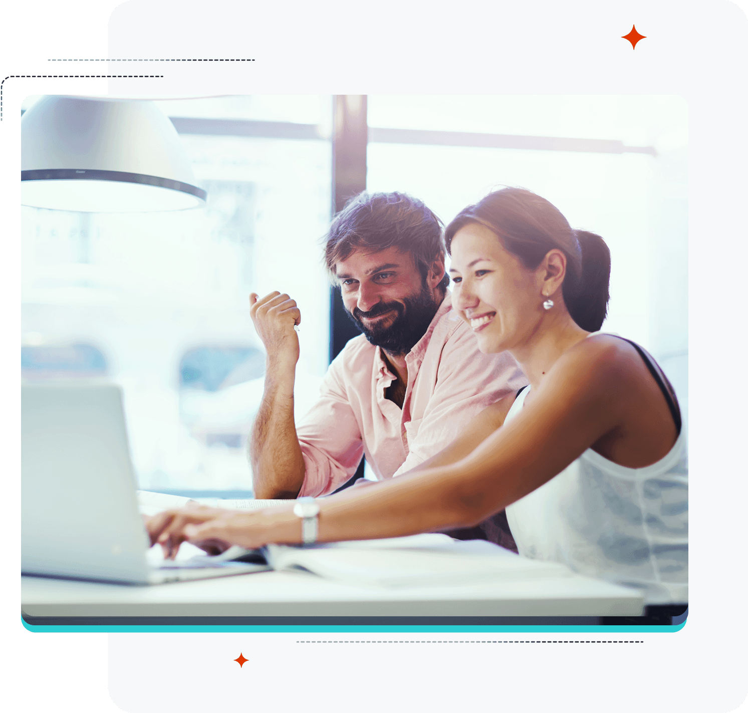 a man and a woman sit at a table looking at a laptop