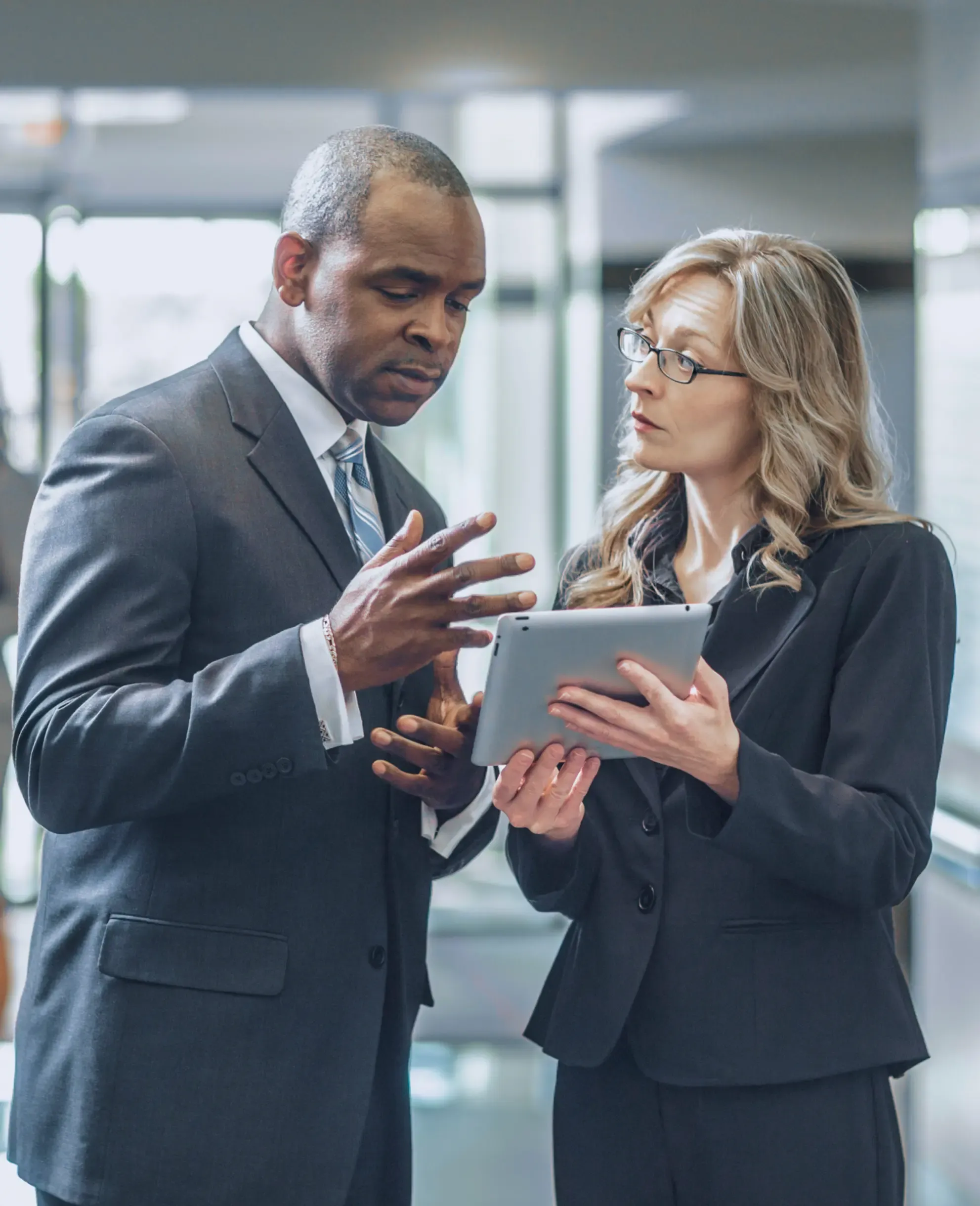 Two workers discussing while looking at a tablet.