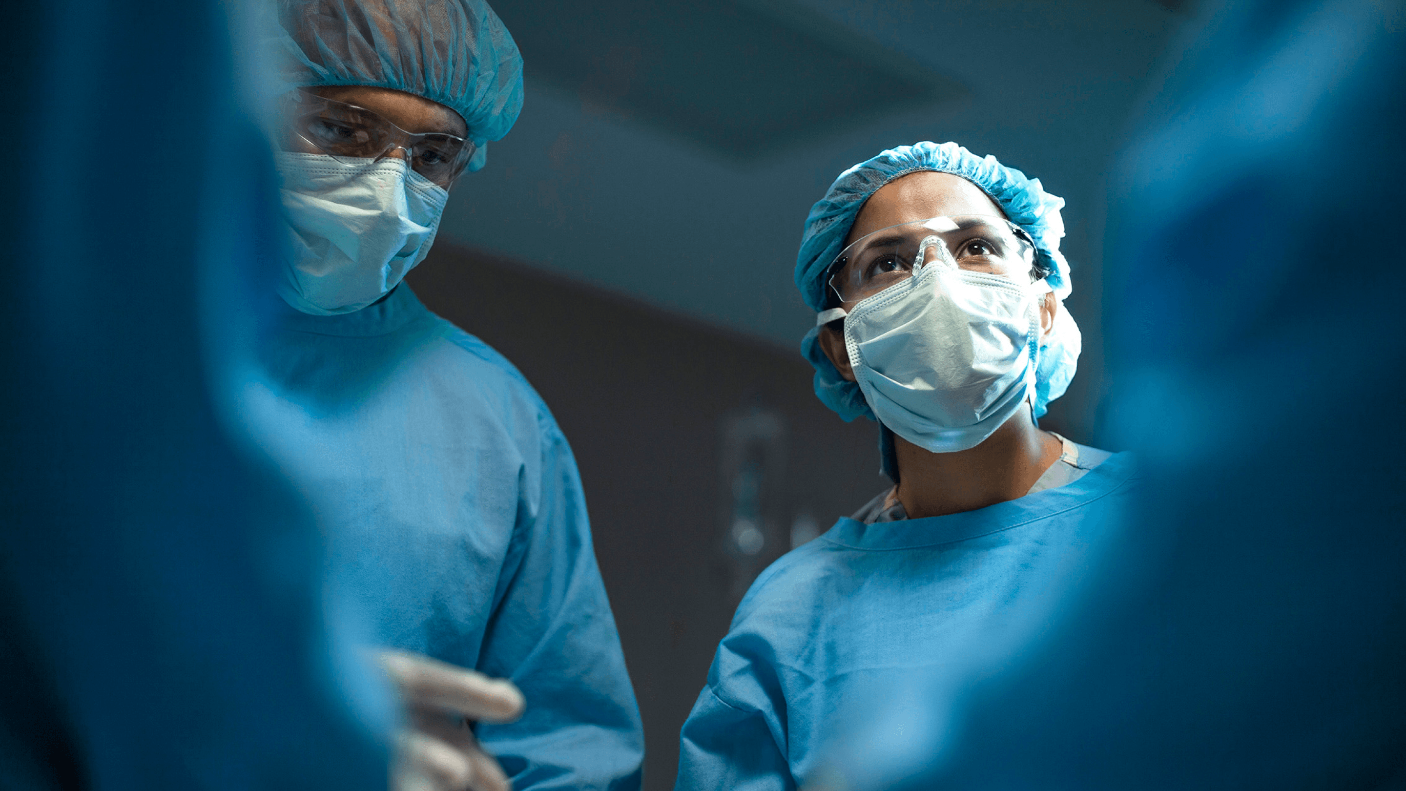 Image of two healthcare workers wearing surgical gear.