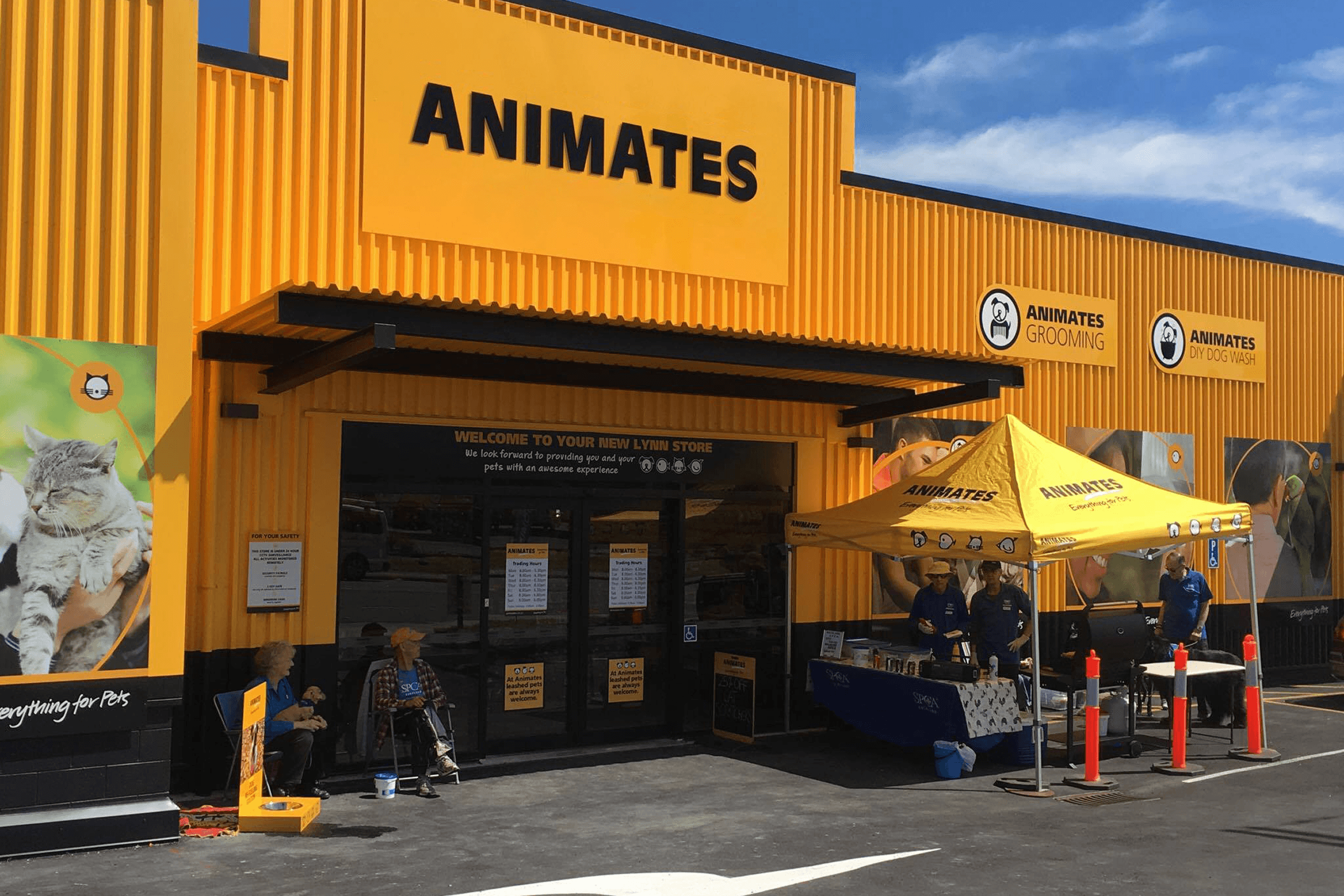 Exterior of a bright yellow Animates pet store with an outdoor event tent.