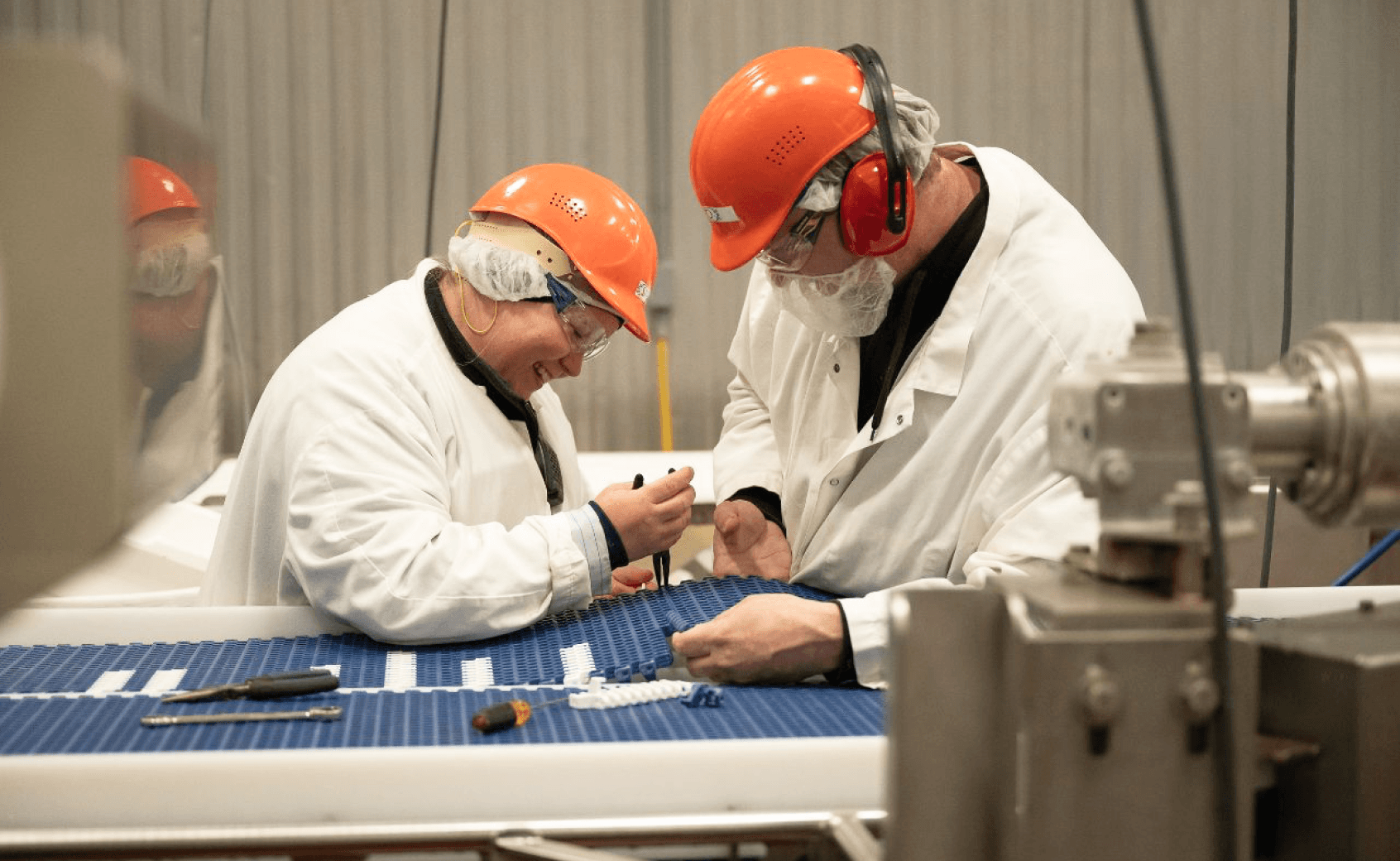 Image of two people working wearing protective gear.