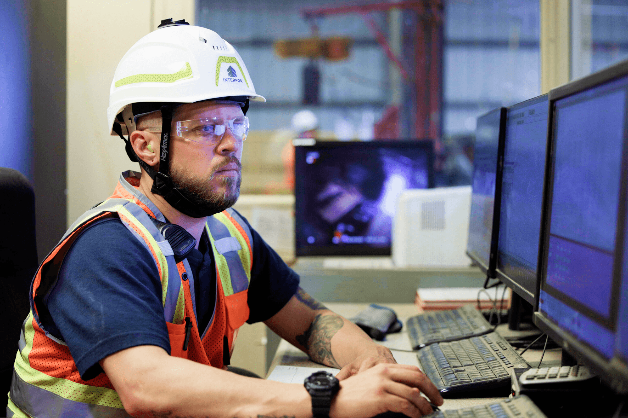 Man in construction gear working at a computer.