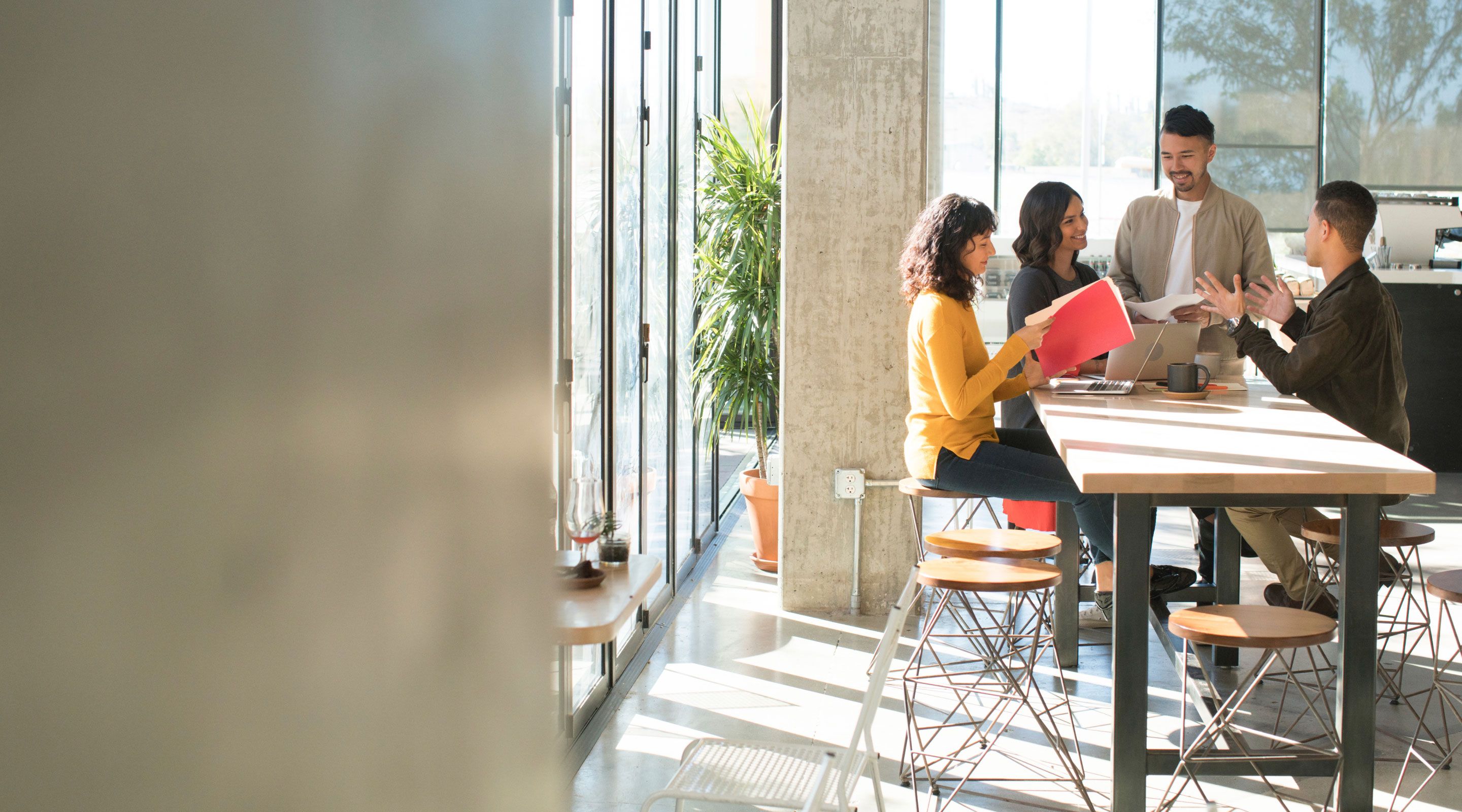 Image a four people working around an elevate table having a discussion.