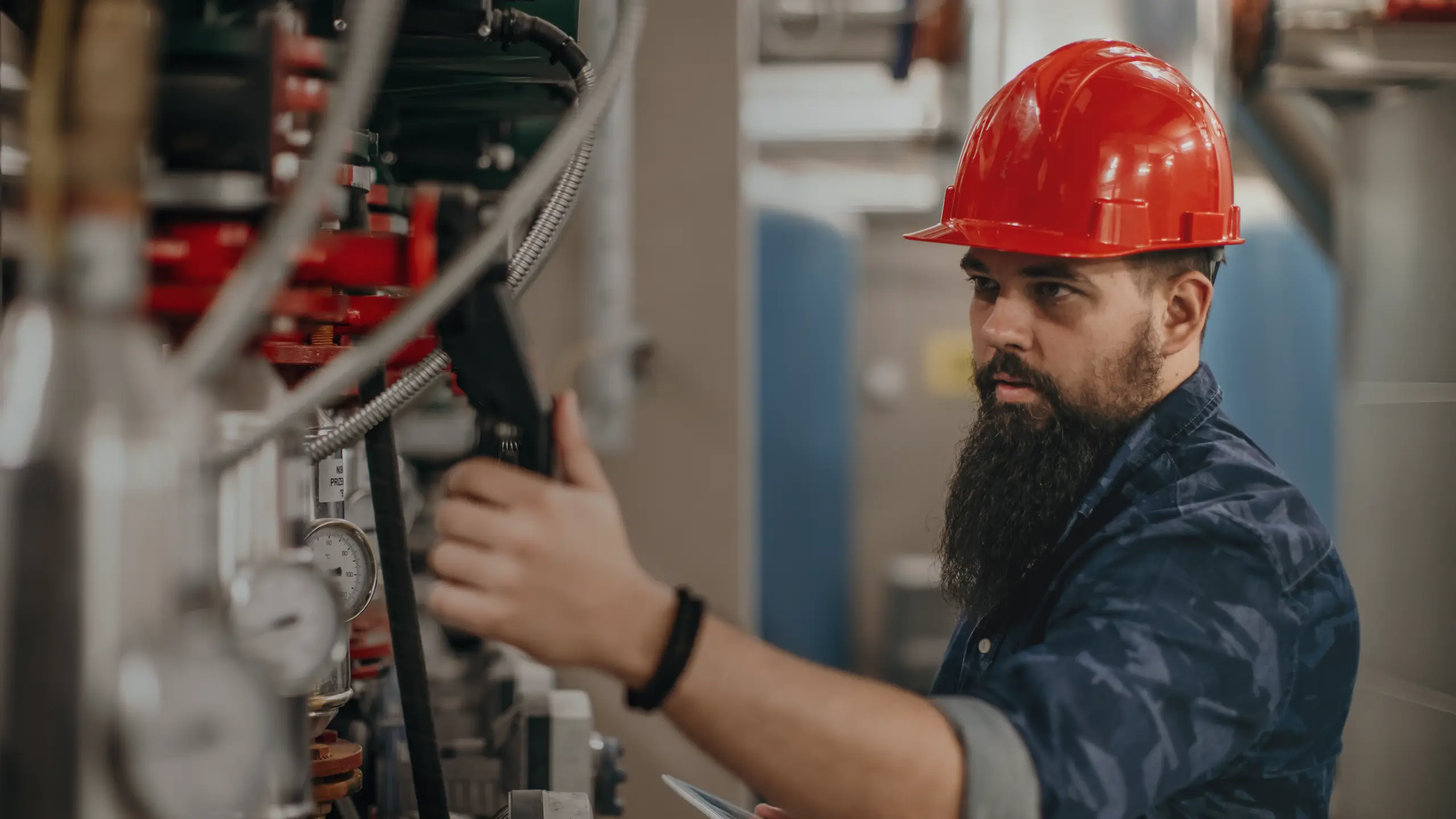 Image of a person wearing a hard hat and working in an industrial environment.