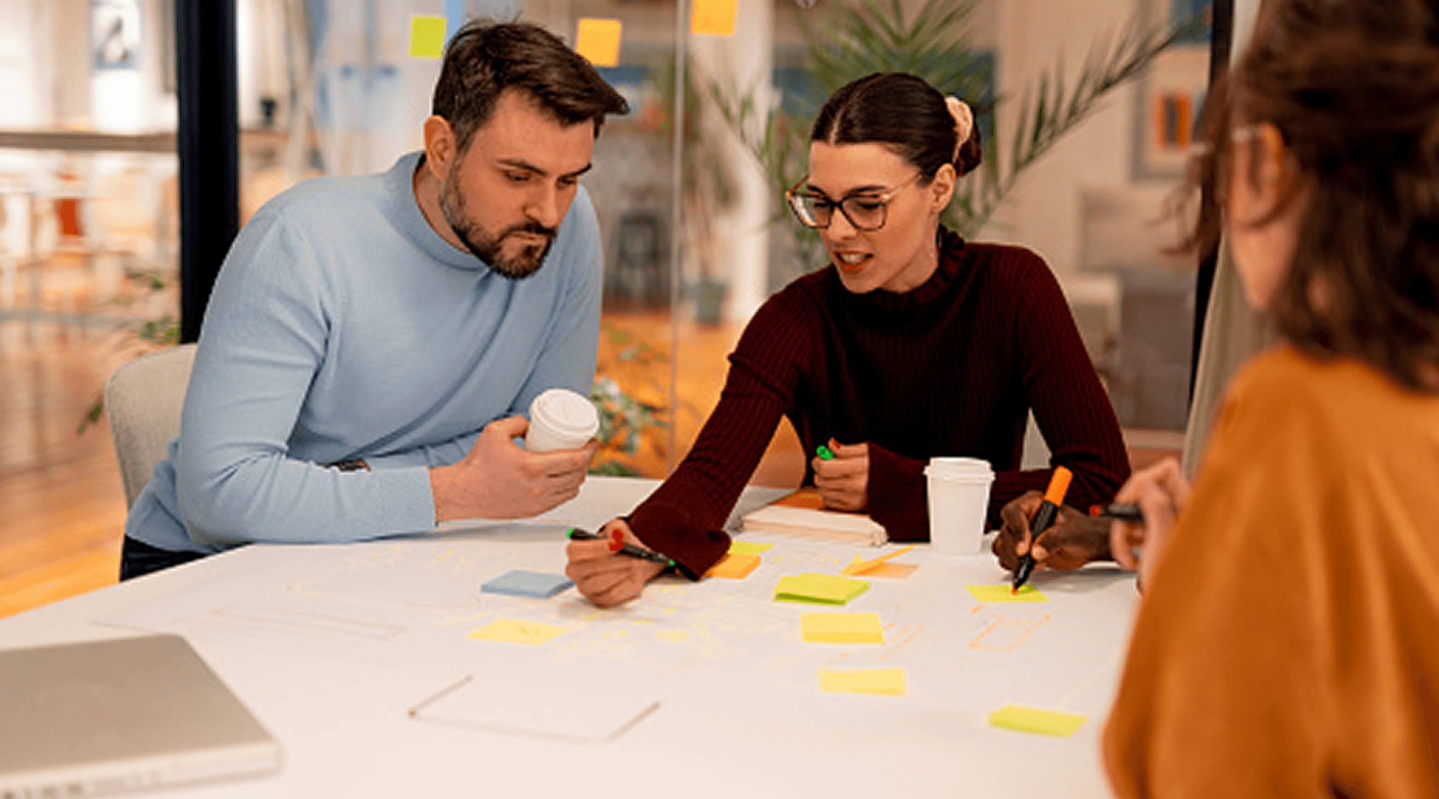 People sitting around a table writing and organizing Post-It notes.