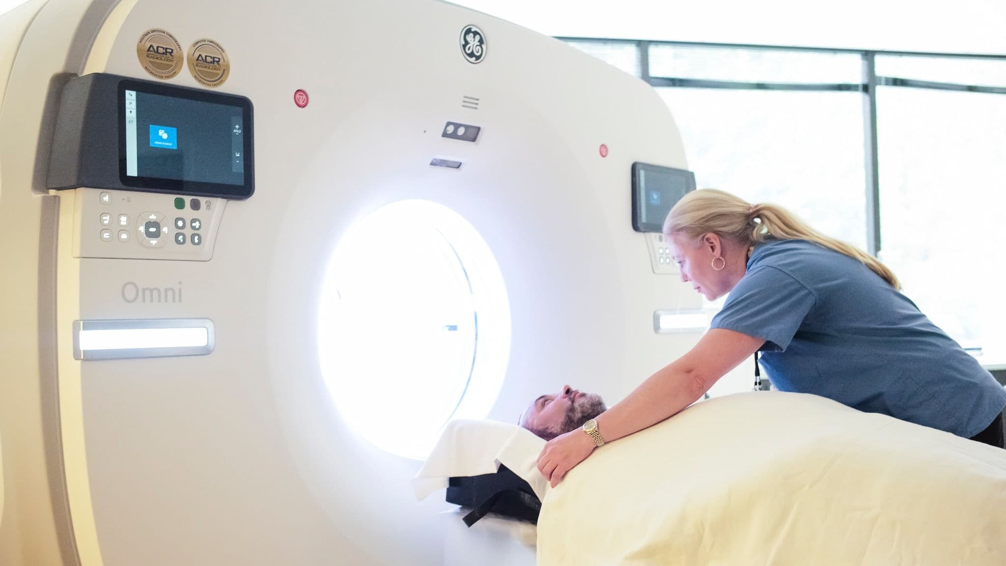 A medical technologist positions a male patient for a GE Omni CT scan.
